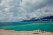 emerald sea against the background of mountains and sky with dark clouds