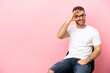 © luismolinero - Young man sitting on a chair over isolated pink background showing ok sign with fingers