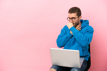 Young man sitting on a chair with laptop is suffering with cough and feeling bad