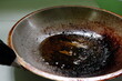 Closeup of burnt, scorched and greasy pan or wok with cooking oil in kitchen.