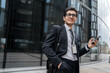 © muse studio - A financier uses a phone, writes a message to a colleague, a man with glasses goes to the office to work, in a business suit