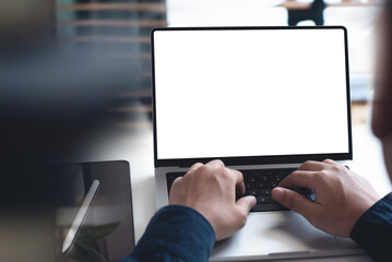 Wall Mural - mockup, blank screen laptop computer. Business man working on laptop computer on table at office. mock up for website design and digital marketing, over shoulder view