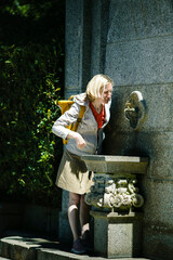 A woman tourist drinking from a medieval drinking fountain.