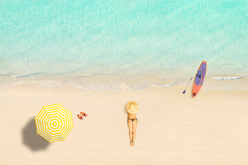 Top view of woman in bikini lying near umbrella and sunbathes on tropical Seychelles sea sand beach with SUP board for surfing. Aerial, drone view