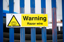 Razor Wire Warning Sign On Security Fence At Construction Site