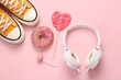 Headphones with sneakers and sweets on a pink background. Minimal youth still life. Top view