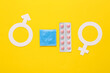 Condoms packaging and blister of birth control pills, male and female gender symbol on yellow background