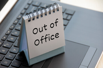 Out of office text on calendar desk on top of a laptop.