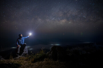 Wall Mural - man sit down on stone at night. milky way galaxy at night.