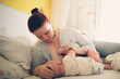 © natalialeb - Breastfeeding. Plus size mom breastfeeds baby on bed