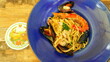 leckerer Teller mit Spaghetti und Meeresfrüchten und Riesengarnele steht auf rustikalem Tisch