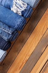 Wall Mural - Jeans heap at wooden background texture. Blue jeans denim fabric on tabletop