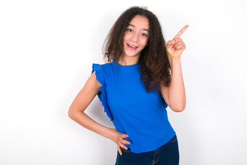 Teenager girl with afro hairstyle wearing blue T-shirt over white wall  holding finger up having idea and posing