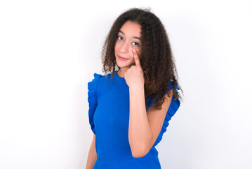 Wall Mural - Teenager girl with afro hairstyle wearing blue T-shirt over white wall  Pointing to the eye watching you gesture, suspicious expression.