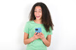 © Roquillo - Teenager girl with afro hairstyle wearing green T-shirt over white wall taking a selfie  celebrating success