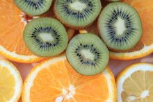 Sliced Kiwi Laid Out On Slices Of Orange And Lemon. Ripe Fruits Stacked Together, Top View. Ingredients For Fruit Salad And Fresh Juic