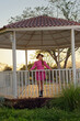 © sandor - Mexican woman in pink dress in a pavilion in a country setting at sunset.