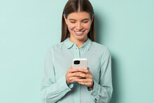 Smiling charming Caucasian student girl using mobile phone isolated over blue background