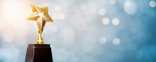 Golden Trophy Award Bokeh Soft  Blue Background. Copy Space For Text. Winner Or 1st Place Gold Trophy Award Concept