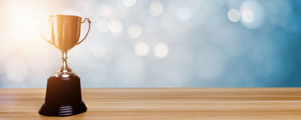 Wall Mural - golden trophy award bokeh soft blue background. copy space for text. winner or 1st place gold trophy