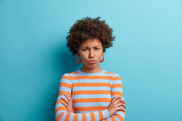 Wall Mural - Sulking displeased offended woman has upset expression keeps arms folded wears casual striped jumper doesnt want to heat your explanations has quarrel with boyfriend isolated over blue background