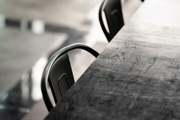 Wall Mural - A black metallic retro style chair with counter table in restaurant. Interior furniture object photo. Close-up and selective focus.