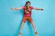Cheerful redhead man in Hawaiian necklace jumping against blue background