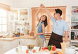© NaMong Productions - Asian husband and wife enjoy cooking salad and dancing together in kitchen room at home.