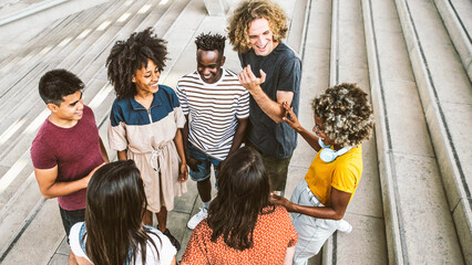 Wall Mural - Group of multiracial young people having fun together on city street - Happy international students socializing in college campus - Friendship concept with guys and girls hanging outside