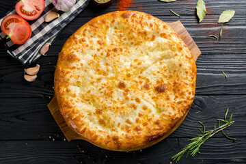 Wall Mural - khachapuri with cheese, megrelian khachapuri, georgian cuisine on black wooden table top view