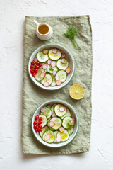 Radish and cucumber salad served in a two bowls on the linen napkin