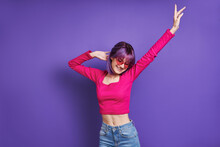Happy Young Woman Dancing While Standing Against Purple Background