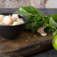 Wall Mural - bowl with raw scallops on a wooden board