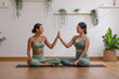 © 220 Selfmade studio - Couple Asian young woman sitting on yoga mat and hi five after doing breathing exercise yoga together.Happiness of two healthy female relax after finished workout at cozy home.Healthy lifestyle