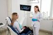 © Tania - She is sitting in the dentist's chair. The dentist explains and advises the patient.