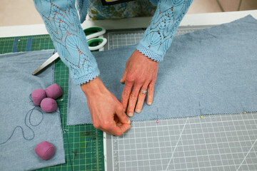 Woman's hands pinning pins into fabric on a table