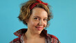 Smiling cheerful pin-up woman in a plaid shirt on a blue background. grown woman