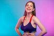 © Yuriy Shevtsov - Smiling sporty woman in fitness sportswear with hands on waist. Female fitness portrait isolated on neon multicolor background.