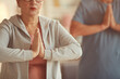 © Mediaphotos - Close-up of calm senior woman in sports shirt holding hands in mudra while achieving mindfulness with meditation at yoga class
