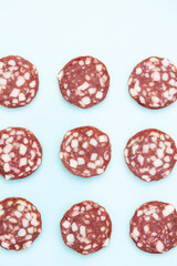 Wall Mural - Top and side views of smoked salami sausage slices isolated on blue background