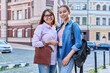 © Valerii Honcharuk - Portrait of happy mom and teenage daughter looking at camera outdoor on city street
