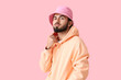 © Pixel-Shot - Fashionable bearded man wearing hoodie and hat on pink background