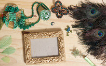 Green Jewelry And Peacock Feathers With Gold Picture Frame On Wooden Table