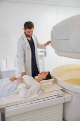 Wall Mural - Radiologist controls MRI or CT or PET Scan with female patient undergoing procedure