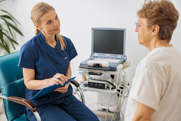 Wall Mural - Doctor ultrasound specialist makes notes in clipboard during patient appointment in clinic