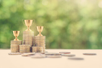 Portfolio management champion / money or asset investment winner, financial concept : Golden trophy on rows of rising coins, depicts great performance a manager manage a portfolio for highest profit