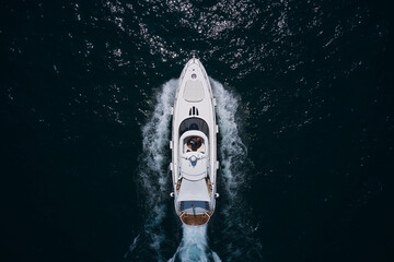 Wall Mural - White yacht on the sea aerial view. Superyacht is moving fast on the water top view. Motor Yacht in motion top view. A huge super Mega yacht in white on dark blue water in Italy.