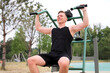 © Евгений Шемякин - portrait of handsome happy strong athletic man athlete bodybuilder training outdoors at open air gym at summer, gain hands and shoulders muscles. Bodybuilding and fitness, healthy lifestyle
