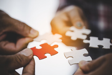 Hands holding piece of blank jigsaw puzzle for teamwork