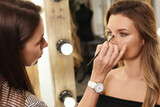 Pofessional make-up artist and her working process during makeup routine for young and beautiful model